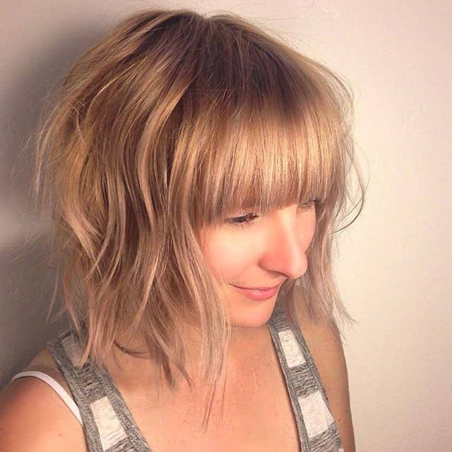 Dark blonde wavy bob with full blunt bangs